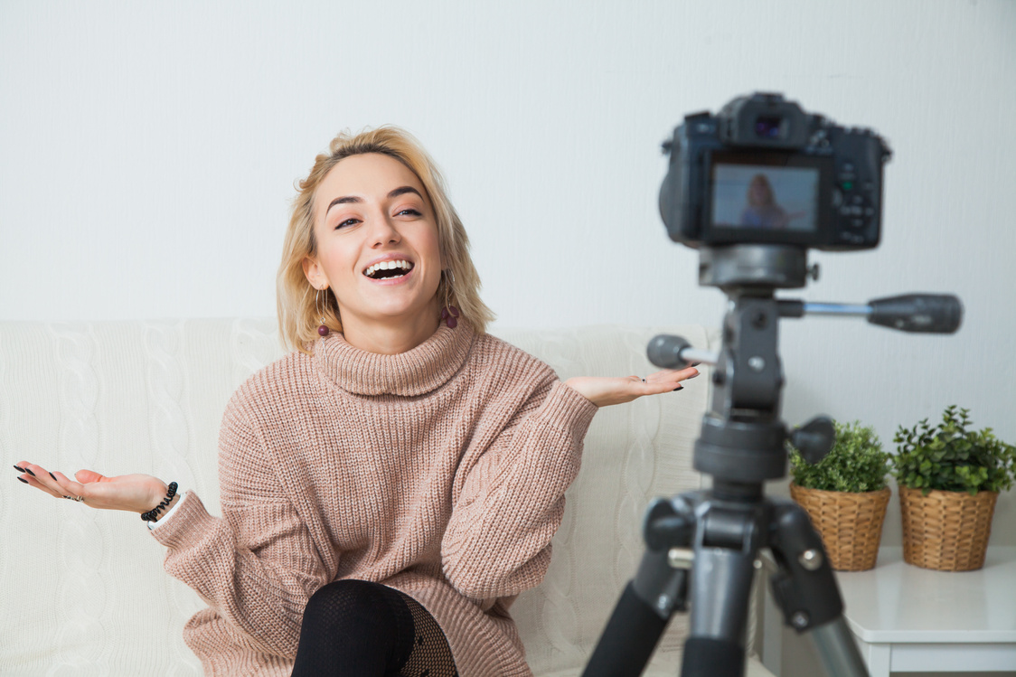 Blogging concept. Young female blogger next to video camera at home.