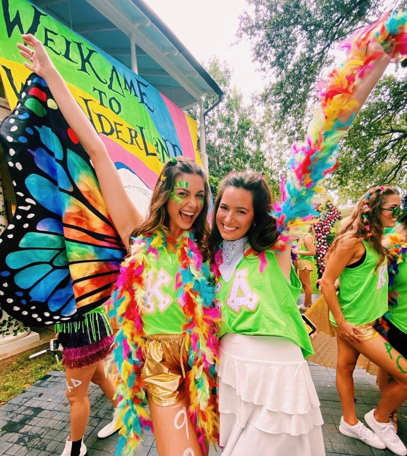 Two people dressed in colorful costumes pose for a photo to celebrate the end of sorority recruitment. 