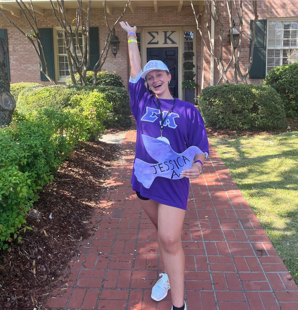 a person wearing a purple Sigma Kappa shirt and holding up their hands