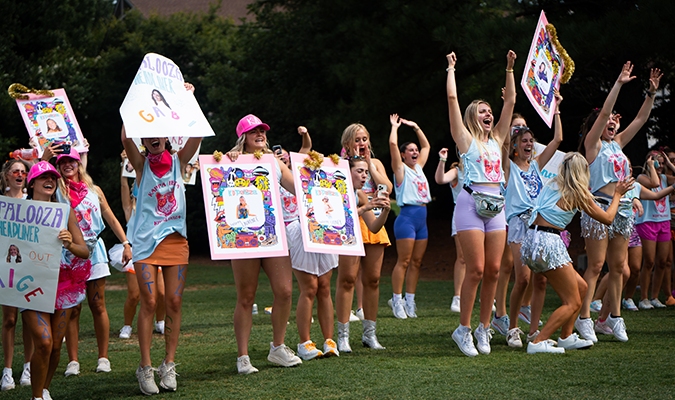 a group of sorority women holding up signs in the grass on bid day